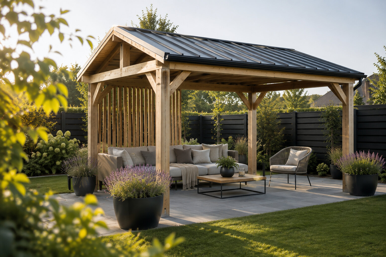 Holzpavillon mit anthrazitfarbenem Blechdach über einer Sitzgruppe auf einer Steinterrasse im Garten